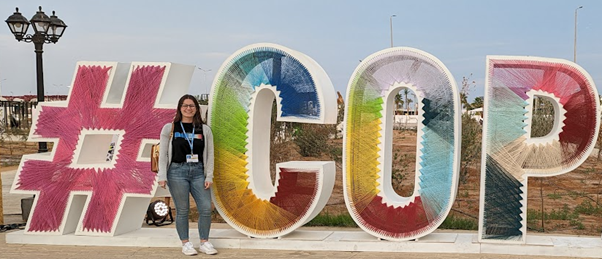 Dannielle Roche standing in from of the COP27 sign